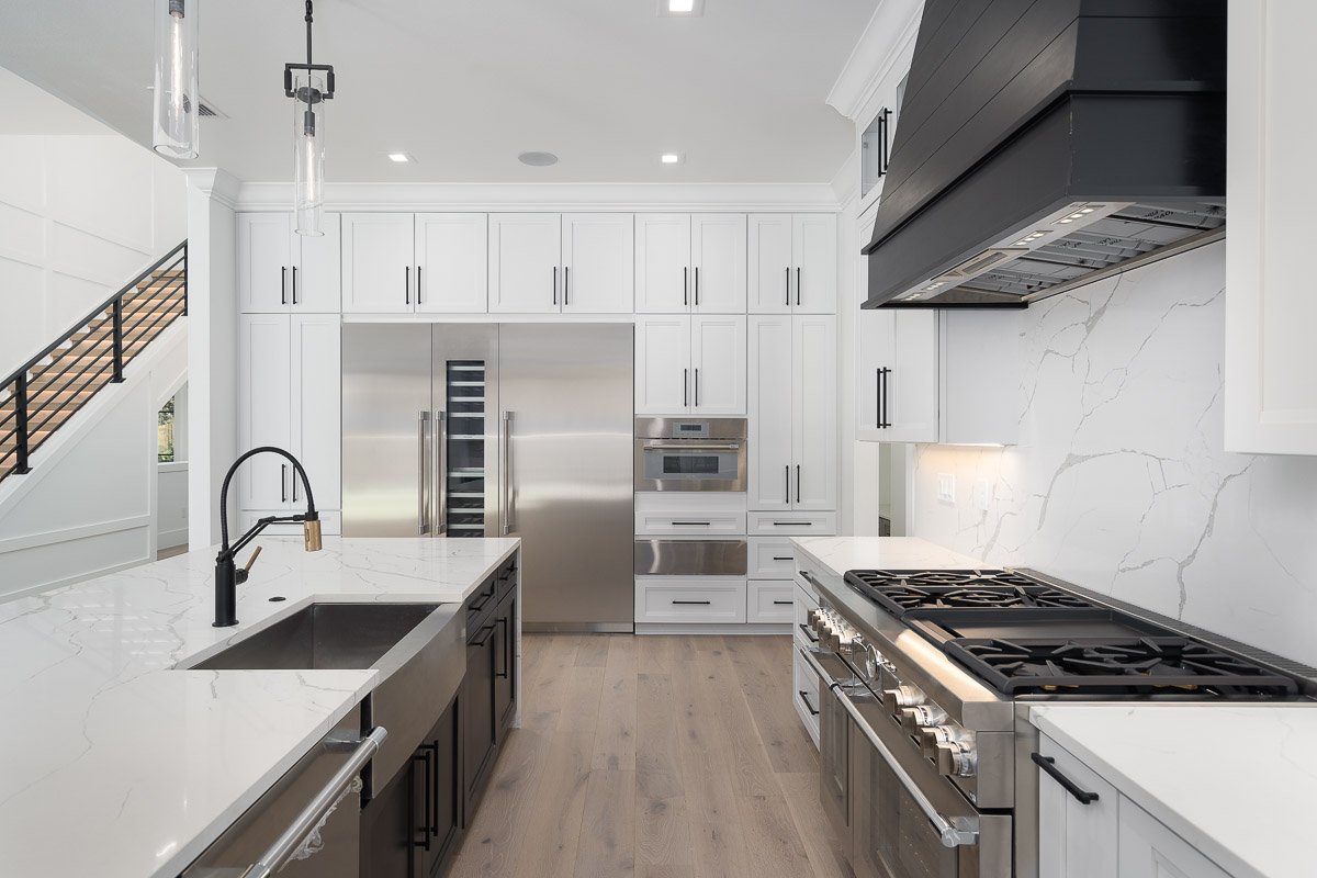 Luxury modern kitchen professionally photographed for a real estate listing, showcasing white cabinets, quartz countertops and high-end appliances.