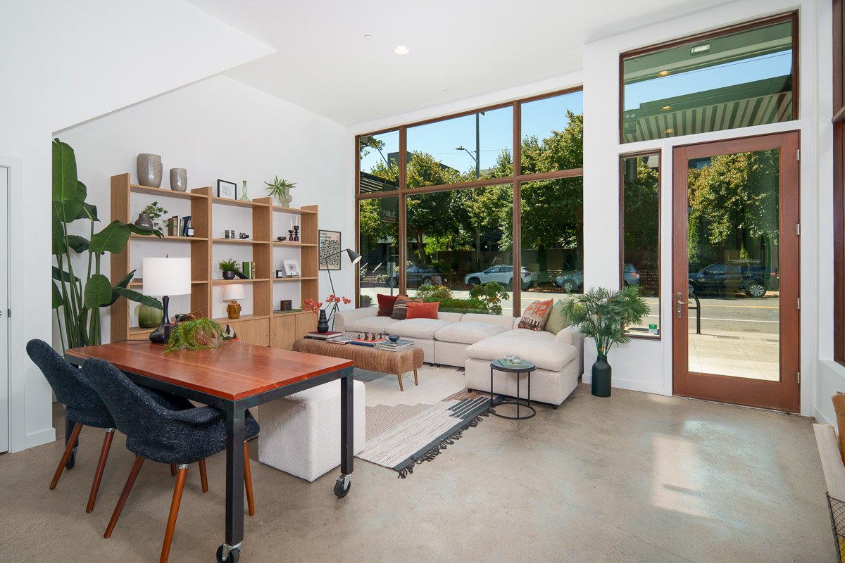 Professional flambient real estate photography of a modern Seattle live-work space with floor-to-ceiling windows, an open living area, workspace, and street-level commercial access.