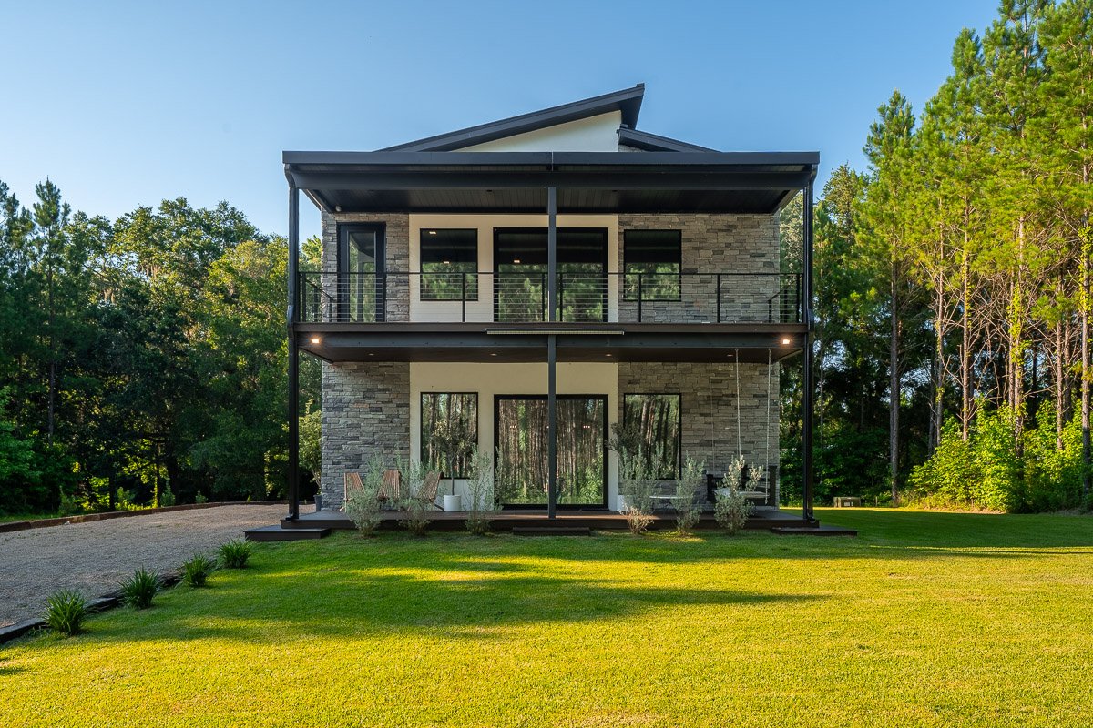 Professional real estate photography of a luxury modern Seattle home with stone exterior, covered balconies, contemporary architecture, and a private wooded setting.