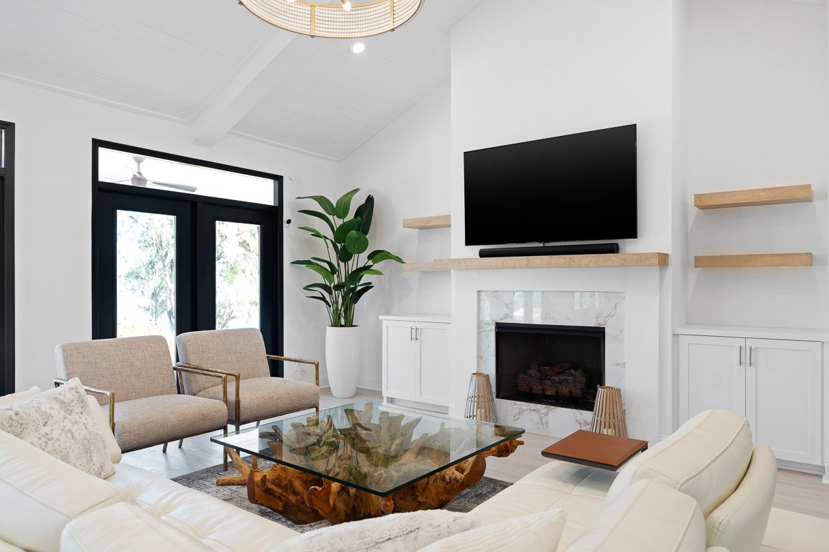 Professional real estate photography of a bright Seattle living room with vaulted ceilings, modern fireplace, built-in shelving, and contemporary furnishings.