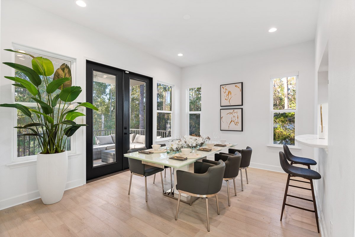 Professional real estate photography of a bright Seattle dining room with modern staging, large windows, French doors, and abundant natural light.