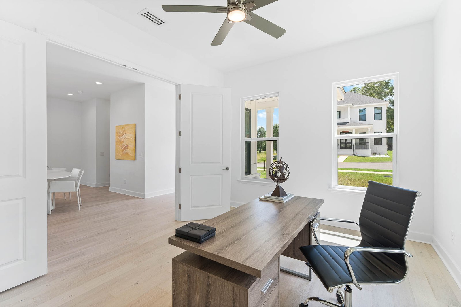 Professional real estate photography of a bright Seattle home office with modern furnishings, large windows, hardwood floors, and natural light.