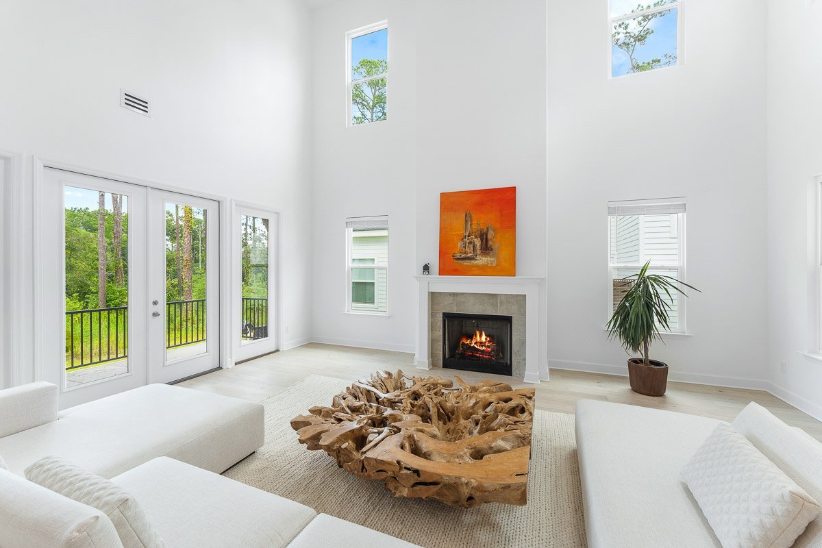 Professional real estate photography of a bright Seattle living room with soaring ceilings, a modern fireplace, large windows, and contemporary staging.