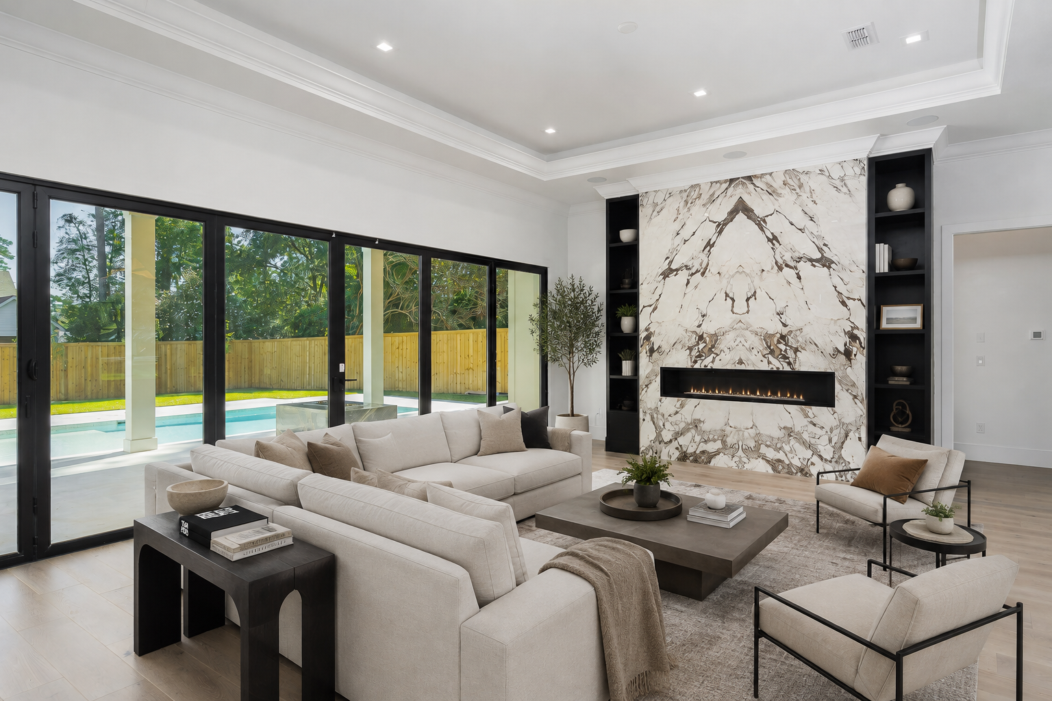 rofessional real estate photography of a luxury Seattle living room with a dramatic marble fireplace, modern staging, floor-to-ceiling glass doors, and backyard pool views.