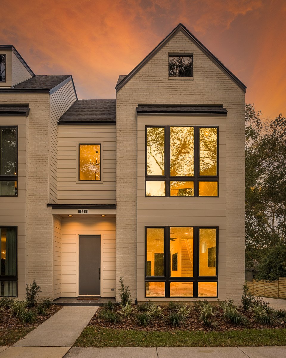 Professional twilight real estate photography of a modern Seattle townhouse with warm interior lighting, tall windows, contemporary architecture, and dramatic sunset skies.