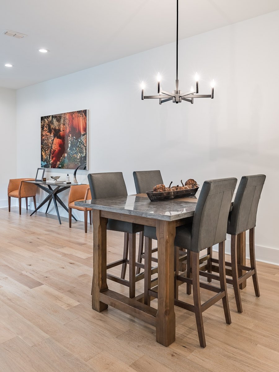 Professional real estate photography of a modern Seattle dining room with contemporary furnishings, statement chandelier, light wood floors, and clean neutral finishes.
