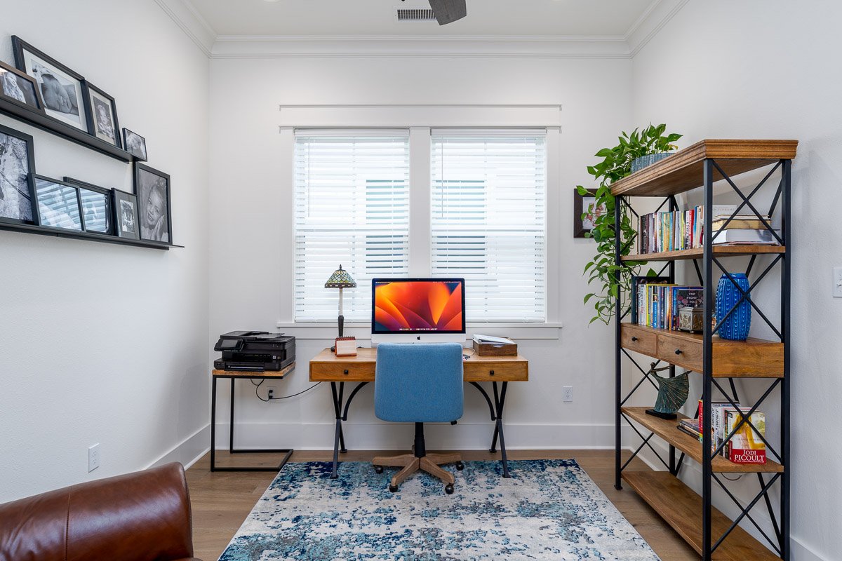 Professional flambient real estate photography of a bright Seattle home office with a dedicated workspace, modern shelving, natural light, and contemporary finishes.